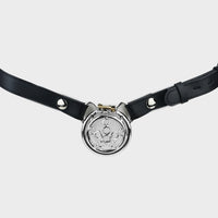 Black leather belt holds a steel chastity cage in place.