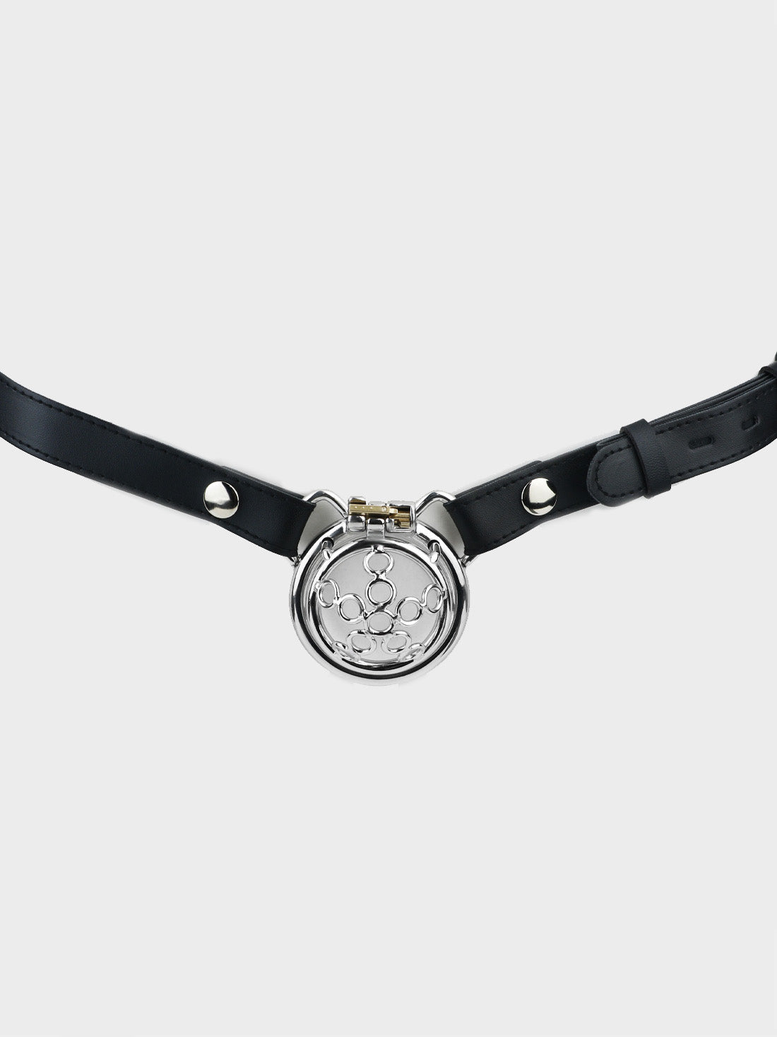 Black leather belt holds a steel chastity cage in place.